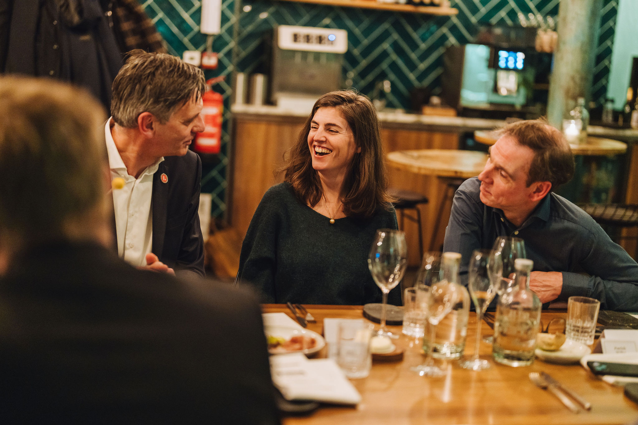 Three guests laughing during dinner